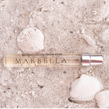 Load image into Gallery viewer, Marbella travel size bottle of Ever Present on a sandy surface with shells 2 shells around it.